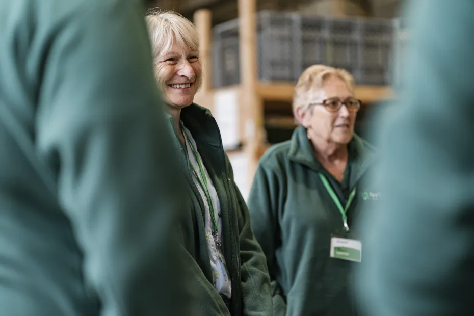 A lady smiling with her team at the Cardiff food bank
