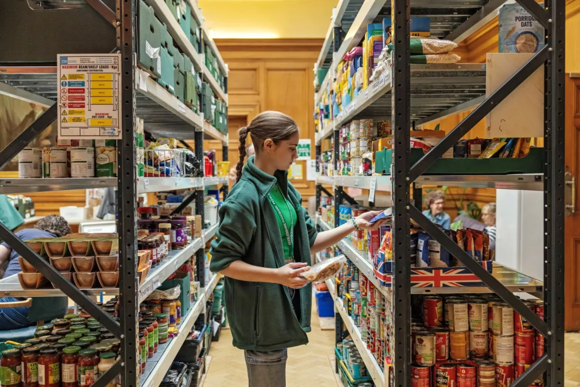 A food bank volunteer sorts through donations on a shelf
